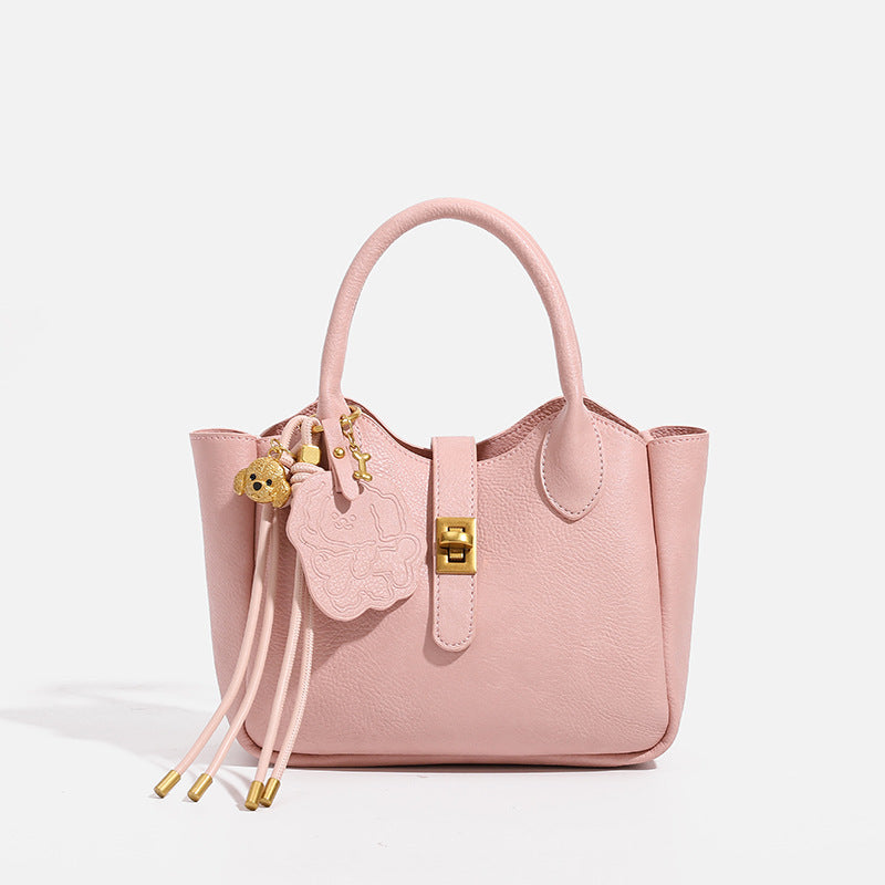 Small structured pebbled leather-look mini tote bag with gold-tone hardware, front toggle closure, knotted bear tassel charm