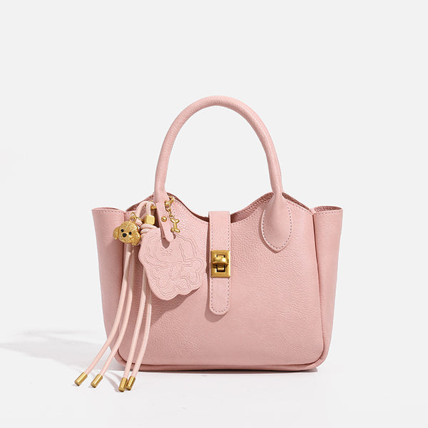 Small structured pebbled leather-look mini tote bag with gold-tone hardware, front toggle closure, knotted bear tassel charm
