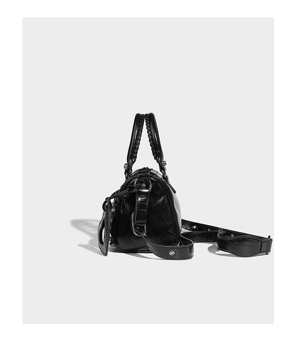 Glossy studded mini satchel bag with braided top handles, front zip pocket, heart charm, and detachable crossbody strap