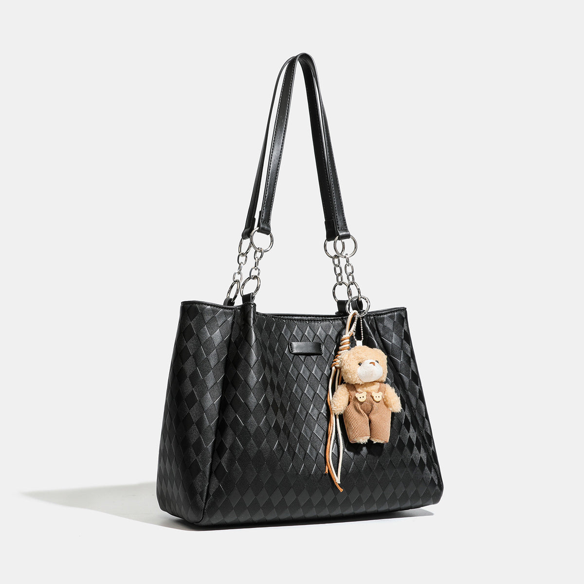 Black diamond-quilted leather-look tote bag with silver chain-ring shoulder straps and plush bear charm pendant, detail view