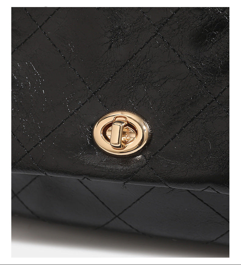 Black glossy diamond-quilted bucket tote bag with gold-tone chain accent, turn-lock front flap pocket, drawstring side ties