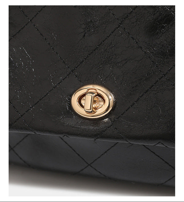 Black glossy diamond-quilted bucket tote bag with gold-tone chain accent, turn-lock front flap pocket, drawstring side ties