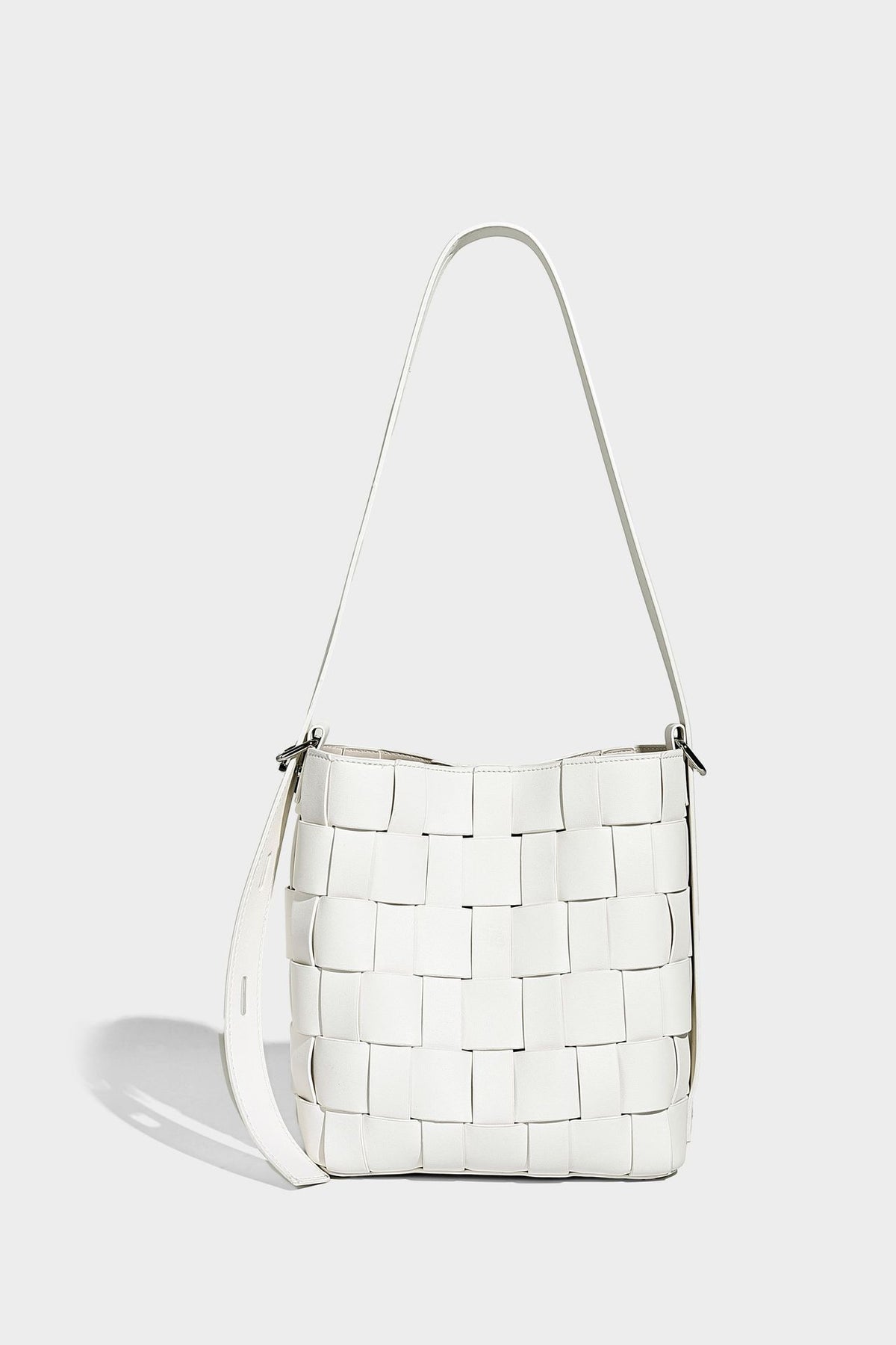 Hand-woven black-and-white checkerboard bucket bag with smooth black trim, silver-tone ring hardware, and adjustable