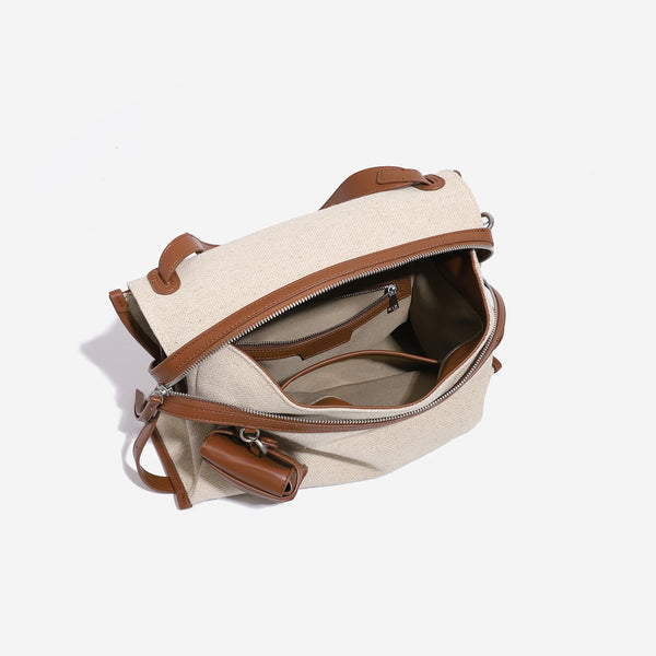 Cream canvas messenger shoulder bag with tan leather-look trim, dual zippers, tassel pulls, and attached mini front pouch