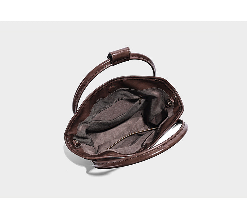 Glossy leather-look structured tote bag with rounded top handles, detachable shoulder strap, embossed front emblem, and side