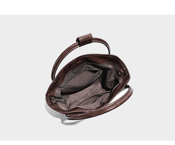 Glossy leather-look structured tote bag with rounded top handles, detachable shoulder strap, embossed front emblem, and side