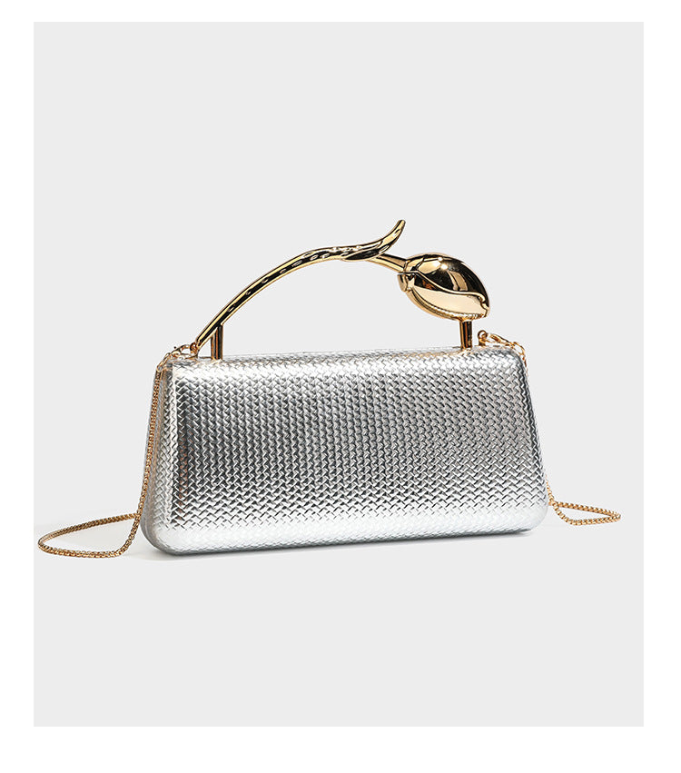 Structured rectangular metallic woven clutch bag with sculptural gold-tone leaf top handle and detachable chain strap, detail