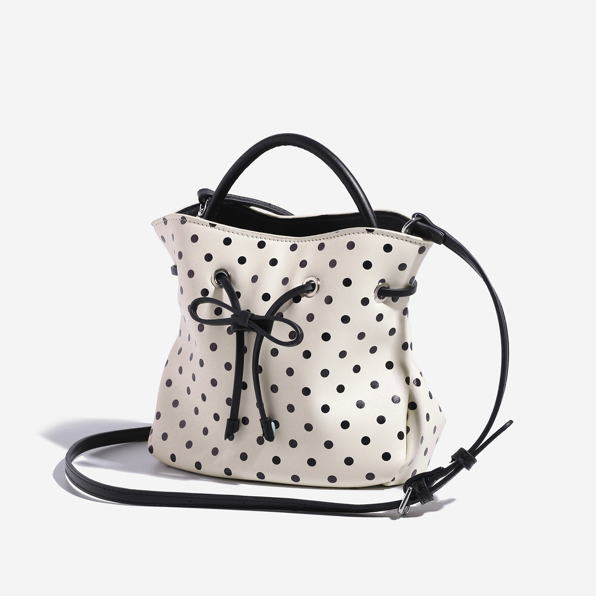 Compact polka-dot drawstring bucket bag with bow closure and rigid top handle, detail view 2