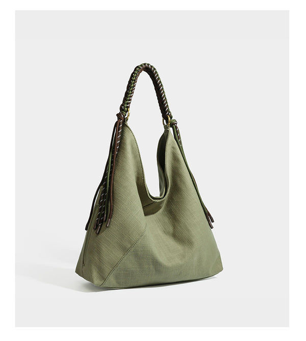 Soft slouchy cream canvas shoulder tote with braided brown and green cord handle, gold-tone ring hardware, and tassel trim