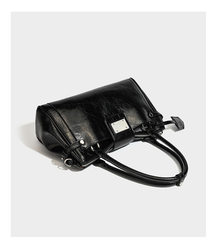 Structured glossy crinkled leather-look satchel with double top handles, front metal-plaque tab, silver-tone hardware, and