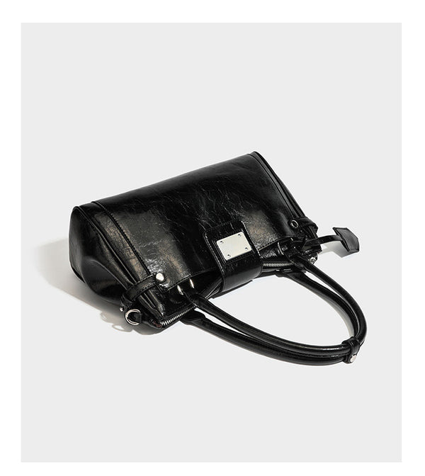Structured glossy crinkled leather-look satchel with double top handles, front metal-plaque tab, silver-tone hardware, and