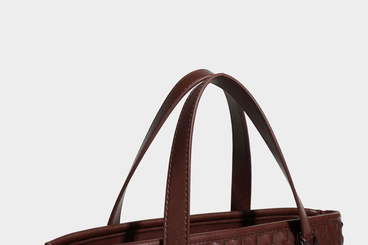 Strukturierte Tote-Bag in Lederoptik mit geprägtem Flechtmuster, zwei Tragegriffen, abnehmbarem Schulterriemen und rundem Perlenanhänger