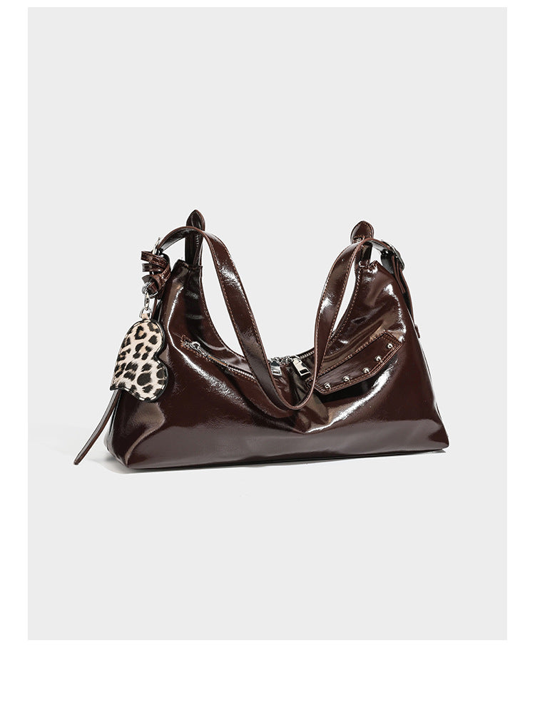 Glossy dark brown hobo shoulder bag with slim strap, front zip pocket, stud detail, and detachable leopard-print heart charm