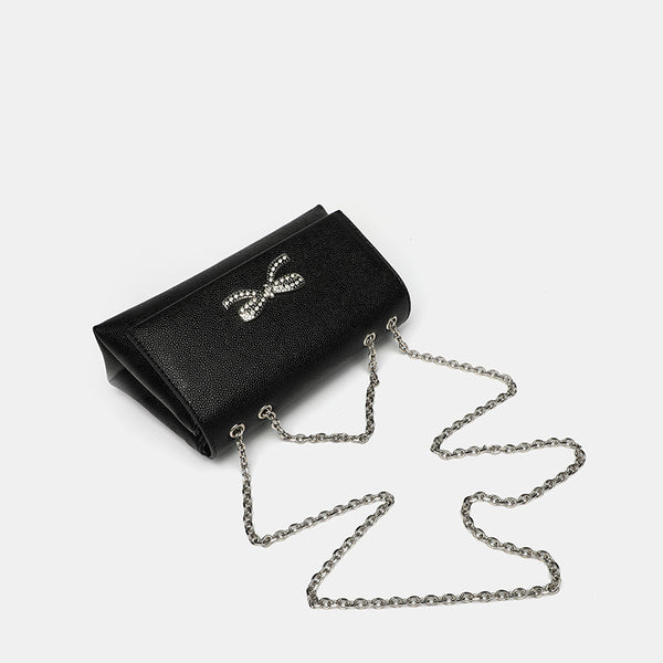 Structured rectangular flap crossbody bag with rhinestone bow and silver chain strap in pebbled finish, detail view 4
