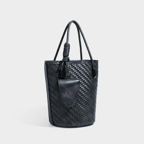 Structured woven-texture leather-look bucket bag in brown with knotted top handles, small front flap pouch, and adjustable