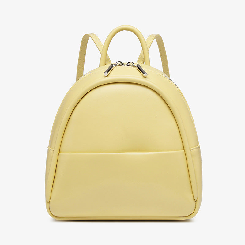 Kleine kuppelförmige Mini-Rucksackhandtasche in Pastellgelb mit glatter Oberfläche in Lederoptik, bogenförmigem Reißverschluss oben und silberfarbenen Details