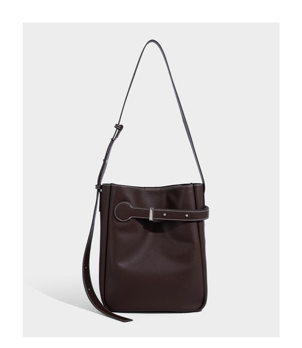 Structured dark brown leather-look bucket bag with white contrast stitching, front wraparound belt buckle strap, and long