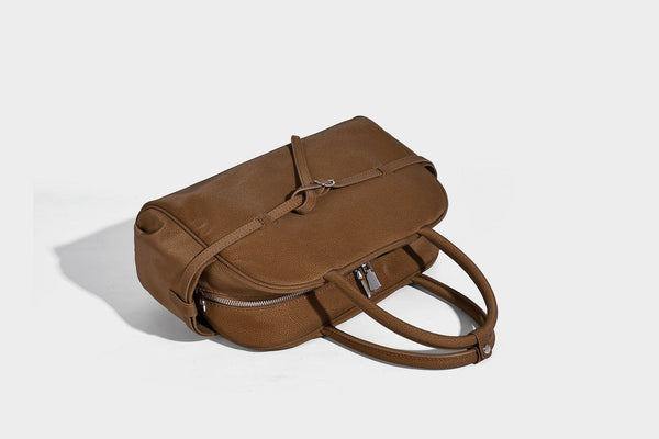 Strukturierte Henkeltasche aus mattem, genarbtem Material mit umlaufendem Riemen und Ringbeschlägen, zwei oberen Tragegriffen und abnehmbarem Crossbody-Riemen