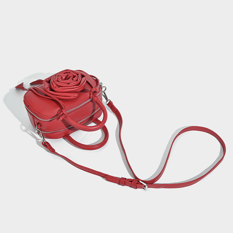 compact barrel bag with 3D rose appliqué, dual zip top, knotted handle, and adjustable crossbody strap, detail view 4