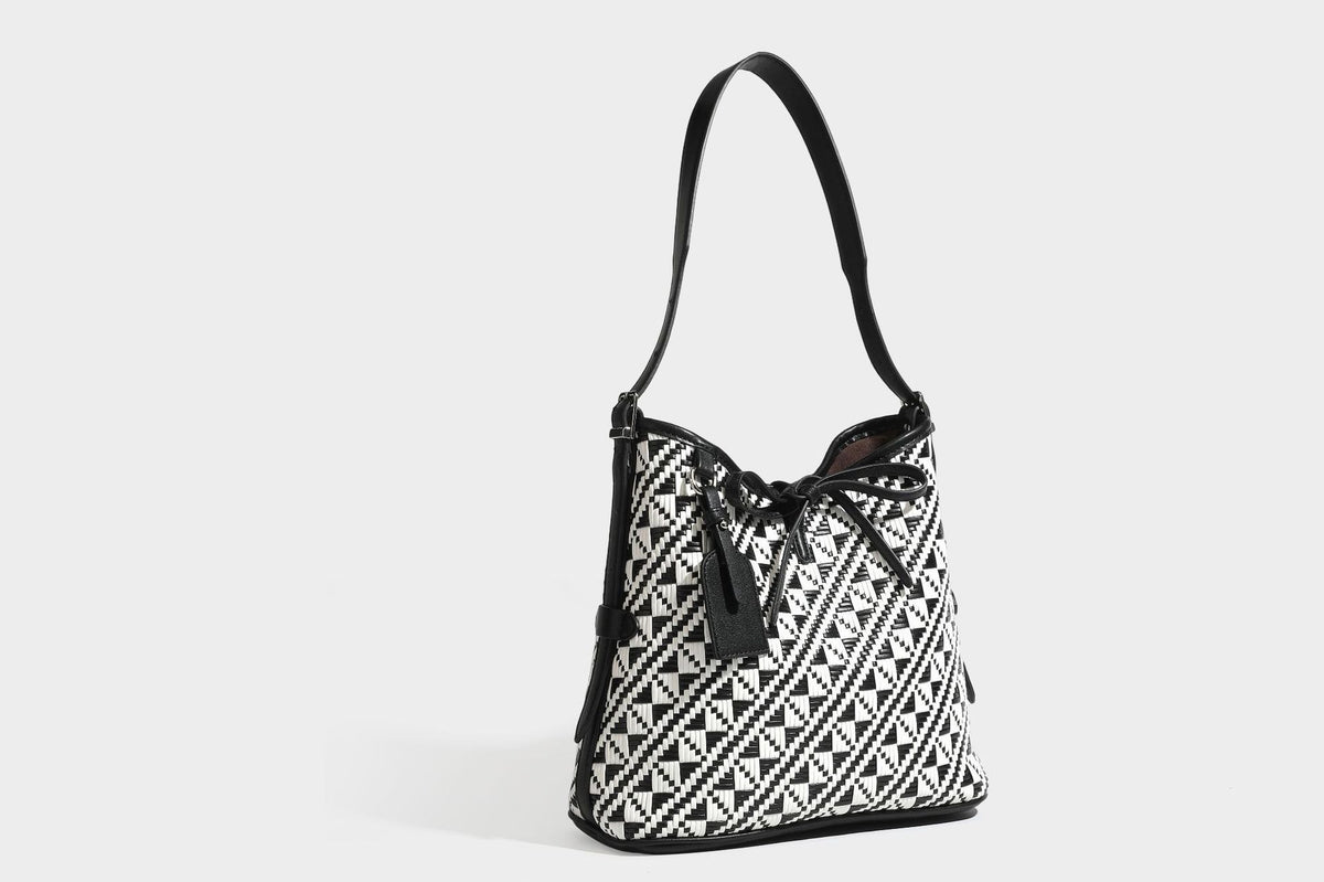 Woven geometric bucket shoulder bag in white and dark brown two-tone pattern with leather-look trim and drawstring top