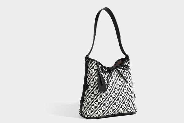 Woven geometric bucket shoulder bag in white and dark brown two-tone pattern with leather-look trim and drawstring top