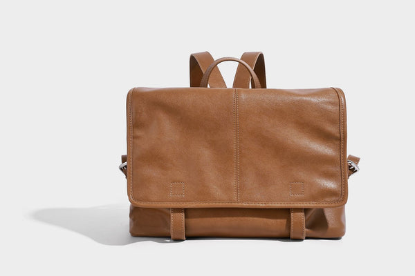 Structured tan leather-look flap backpack handbag with top handle, silver buckle hardware, and fold-over front closure