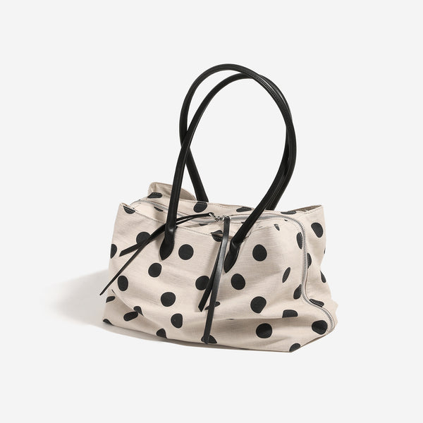 Cream canvas tote bag with black polka dots, rounded leather-look handles, and zip-top closure, detail view 2