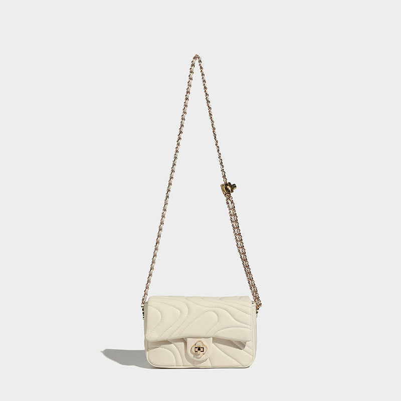 Compact cream quilted flap crossbody bag with wave stitching, gold-tone chain strap, and four-petal turn-lock clasp, detail