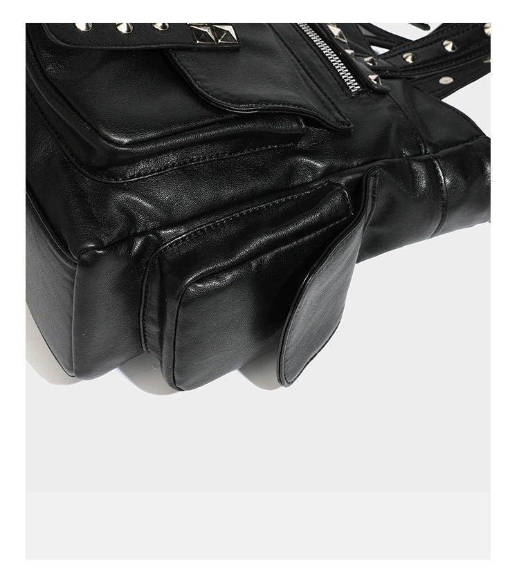 Black leather-look tote bag with silver pyramid studs on handles and front panel, multiple flap and zip exterior pockets