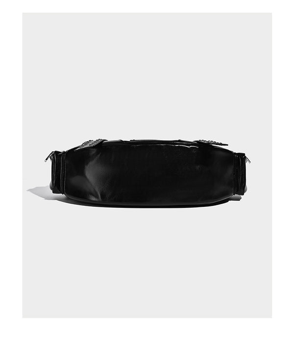 Glossy black crescent shoulder bag with silver-tone rivets, multiple zip pockets, and long adjustable studded straps, detail