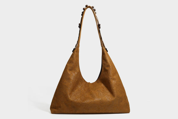 Slouchy boho hobo shoulder bag in embossed brown suede-look finish with beaded strap, cord tassels, and brass-tone leaf