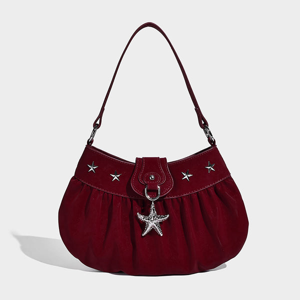 Ruched shoulder bag with curved flap, silver star studs, dangling starfish charm, and adjustable crossbody strap, detail view