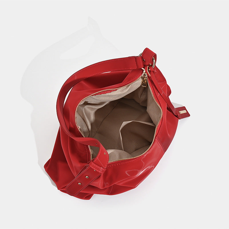Large red glossy leather-look slouchy hobo shoulder tote bag with zip-top closure and gold-tone hardware, detail view 4