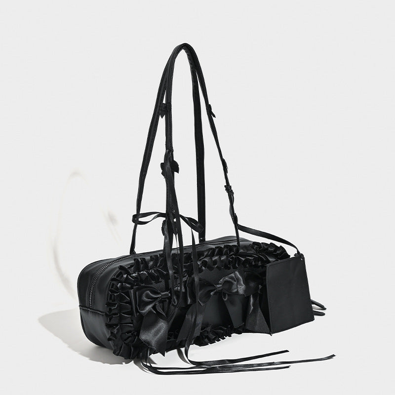 Black leather-look structured tote bag with gathered ruffle trim, ribbon bow accents, top zip closure, and attached card