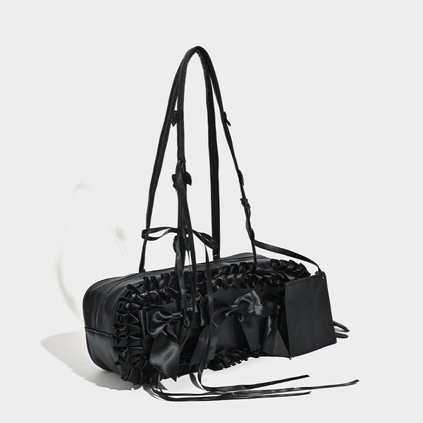 Black leather-look structured tote bag with gathered ruffle trim, ribbon bow accents, top zip closure, and attached card