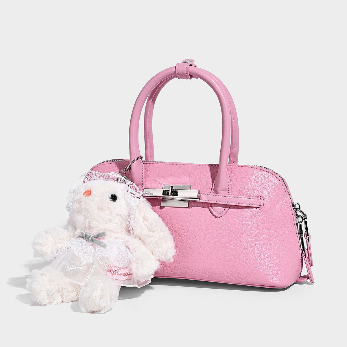 Small structured shell-silhouette top-handle bag with pebbled leather-look finish, silver-tone turn-lock hardware, and