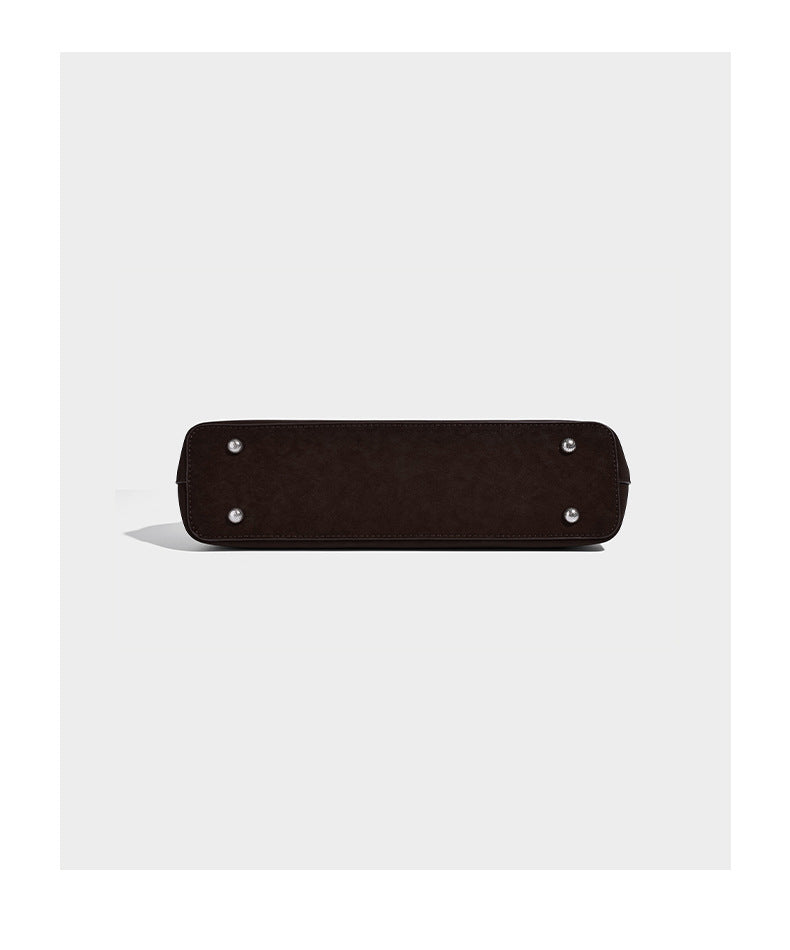 Structured trapezoid shoulder tote in dark brown matte suede-look finish with dual straps, wraparound belt bands