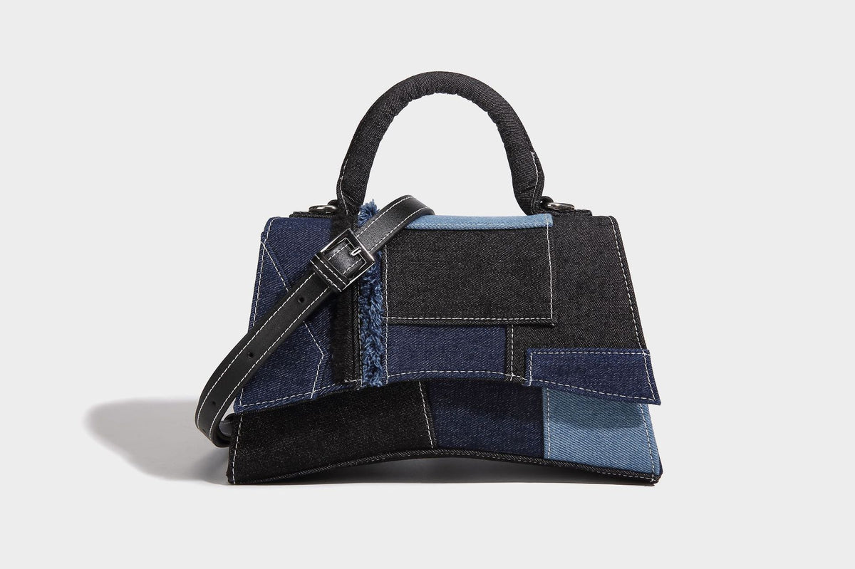 Structured patchwork denim trapezoid satchel bag with frayed panel trim, rounded top handle, and silver-tone hardware, detail