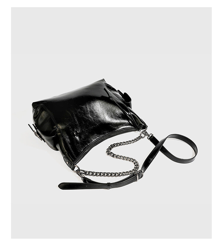 Slouchy hobo shoulder bag with glossy leather-look finish, silver-tone chain drape across front, side buckle pockets, and