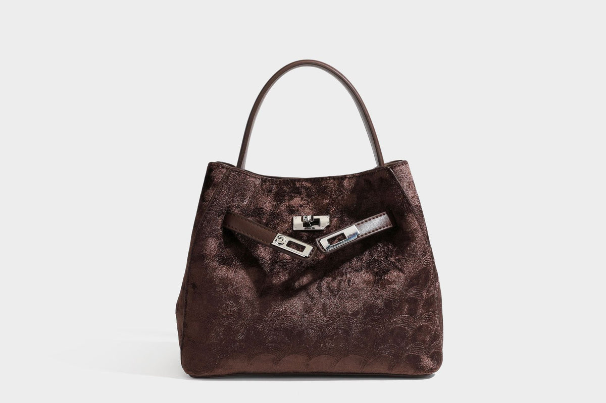 Small structured bucket satchel in embossed velvet-texture fabric with silver turn-lock hardware, rounded top handle, and