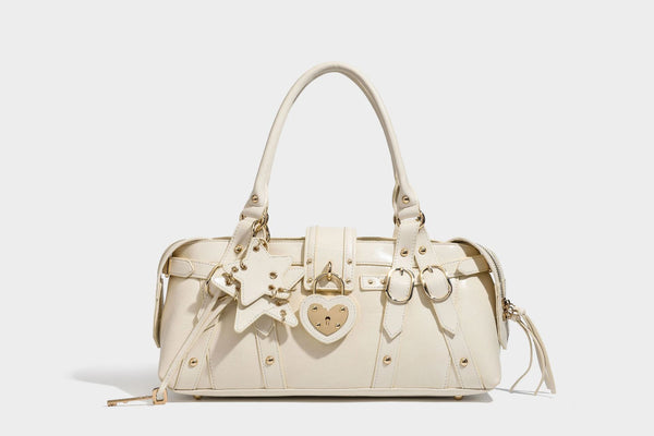 Glossy dark brown structured Boston satchel with heart-shaped lock charm, star pendant, rivet studs, multi-strap front panel