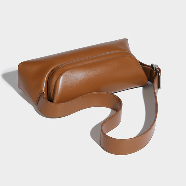 Compact structured baguette shoulder bag with smooth leather-look finish, zip top, and adjustable silver-buckle strap, detail