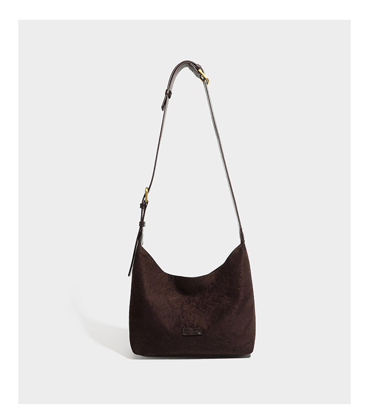 Dunkelbraune, lässig fallende Hobo-Schultertasche mit velourslederähnlich strukturierter Oberfläche, glatter lederähnlicher Paspelierung und Details in Antikgoldoptik, Detailansicht