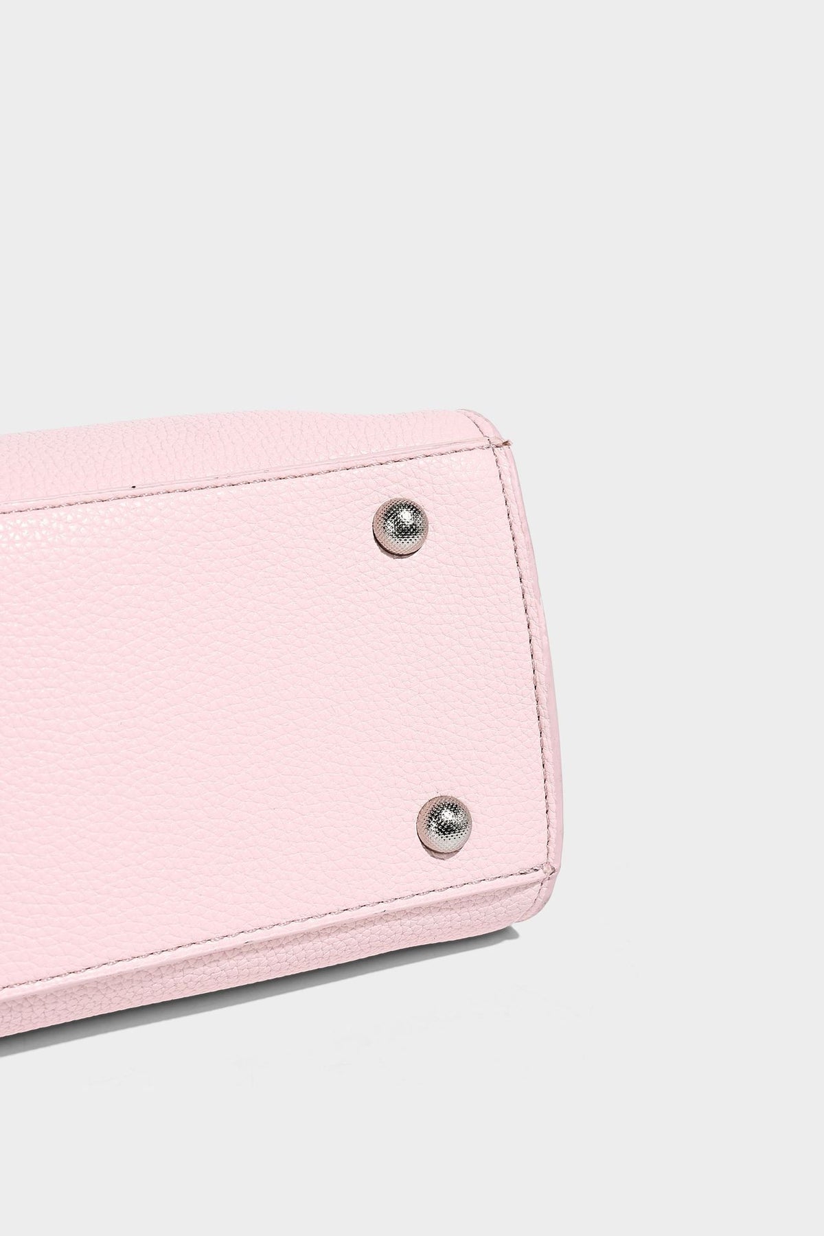 Small structured pebbled-finish shoulder bag with braided top handle, detachable crossbody strap, floral tassel charm, and