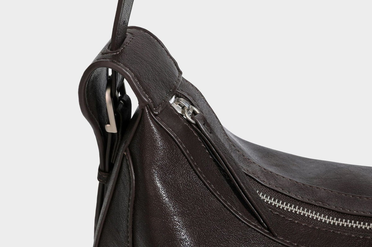 Slouchy crescent hobo shoulder bag in dark brown pebbled leather-look finish with zip top and long shoulder strap, detail