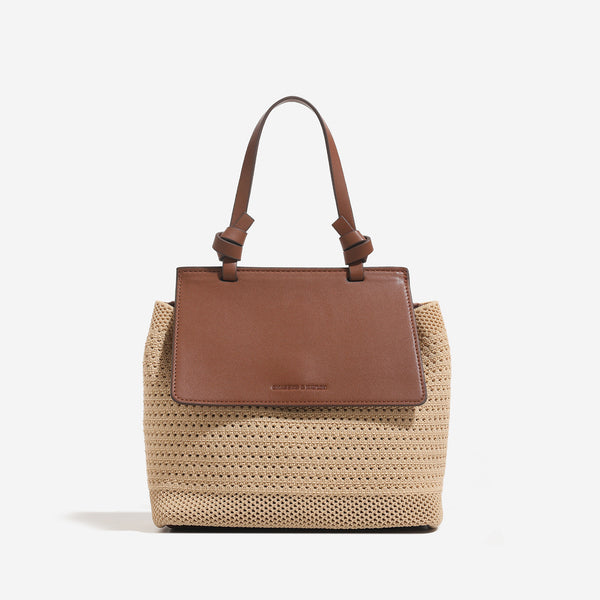 Small structured woven-body flap bag with smooth leather-look front panel, knotted top handle, and wide adjustable shoulder