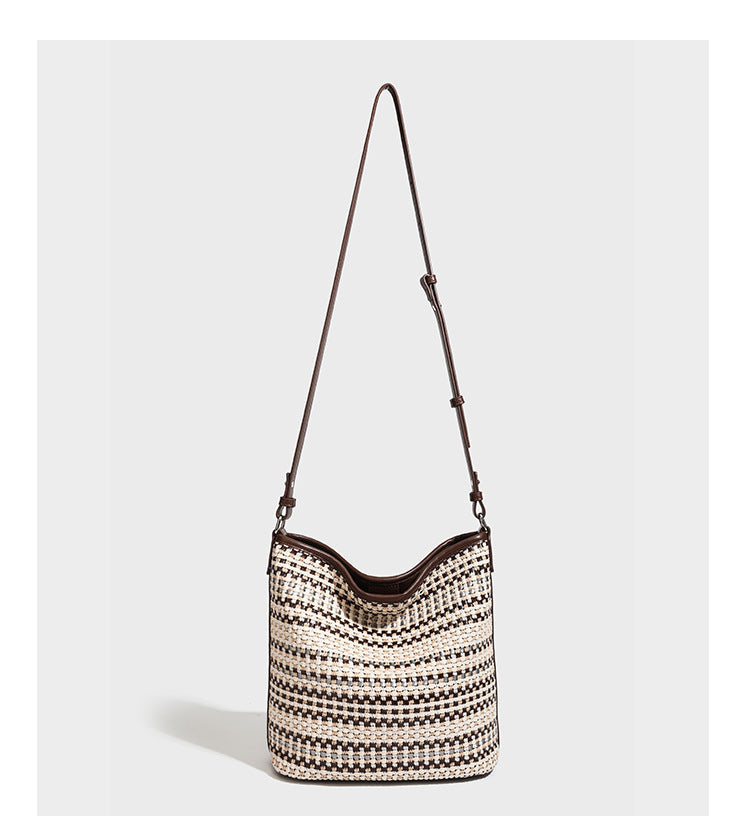 Woven stripe bucket shoulder bag in cream and dark brown with leather-look trim, knotted adjustable strap, and small shield