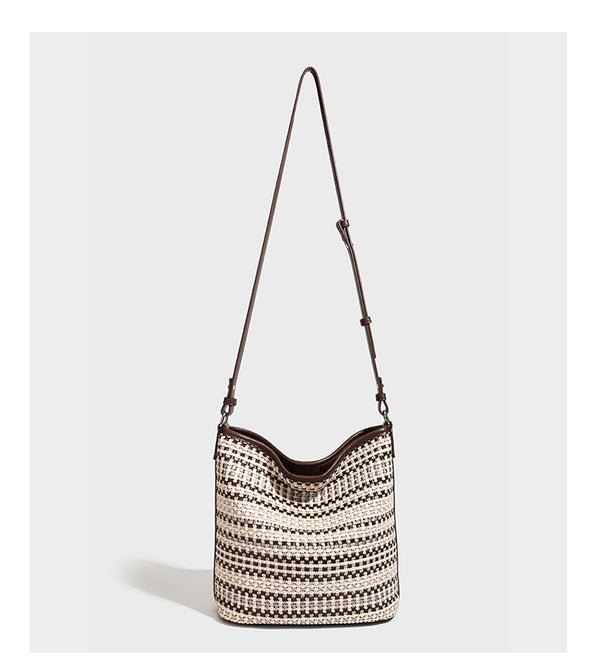 Woven stripe bucket shoulder bag in cream and dark brown with leather-look trim, knotted adjustable strap, and small shield