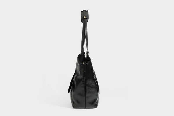Große, glänzende Tote-Bag aus schwarzem Lederimitat mit geknitterter Optik, lässig fallender Trapezsilhouette, zwei Schulterriemen und goldfarbenen