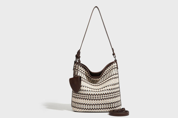 Woven stripe bucket shoulder bag in cream and dark brown with leather-look trim, knotted adjustable strap, and small shield